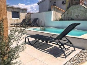une chaise noire assise à côté de la piscine dans l'établissement Holiday home Olive, à Privlaka