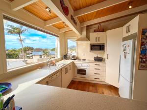 a kitchen with white cabinets and a large window at Princes Retreat in Ngunguru