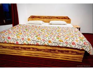 a bed with a floral comforter on top of it at Snow Peak Guest House, Pahalgam in Pahalgām