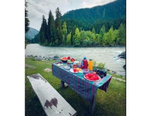 a picnic table with food on it next to a river at Snow Peak Guest House, Pahalgam in Pahalgām