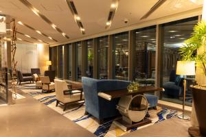 a lobby with chairs and tables and windows at Hotel Ryumeikan Tokyo in Tokyo