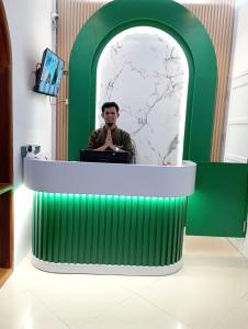a man sitting at a desk in a room at Kareem Syariah Hostel Bukittinggi in Bukittinggi