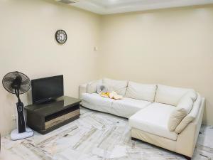 a living room with a white couch and a tv at Kapar Nala 34A /3 Rooms/4-8 pax in Kapar