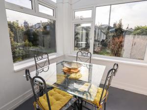 a dining room with a glass table and chairs and windows at The Flat At Brwyn in Holywell