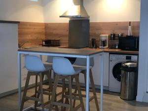 a kitchen with a counter with two blue bar stools at Maison centre historique in Laval