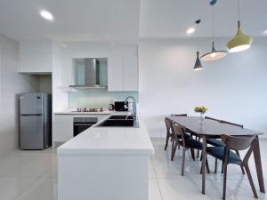 uma cozinha branca com uma mesa e um frigorífico em Iskandar Residences 2BR 5pax 5 mins Legoland Wi-Fi Sky Pool 360 em Nusajaya