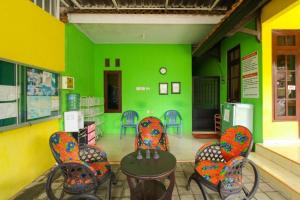 a room with colorful chairs and a green wall at Kampung Osing Inn in Giri