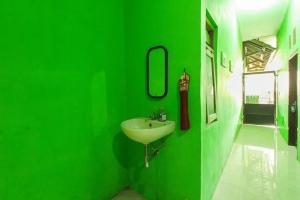 a green bathroom with a sink and a mirror at Kampung Osing Inn in Giri