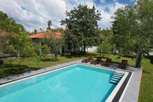 a swimming pool with chairs and a house at Bokka Almeida in Hikkaduwa