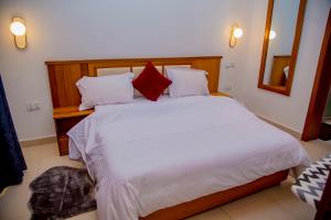 um quarto com uma grande cama branca com almofadas vermelhas em The View Apartments Kigali em Kigali