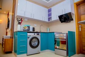 uma máquina de lavar roupa numa cozinha com armários azuis em The View Apartments Kigali em Kigali