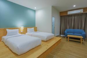 a bedroom with two beds and a blue chair at MOODs Boutique Hotel in Ban Phayom