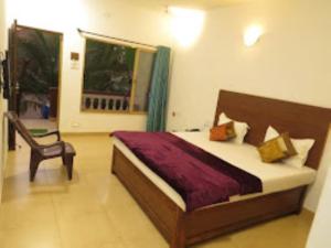 a bedroom with a bed and a chair and a window at Blue Sea Beach Resort Malvan in Malvan
