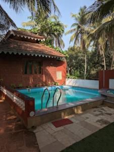 a swimming pool in front of a house at Blue Sea Beach Resort Malvan in Malvan