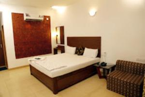 a bedroom with a bed and a chair in it at Blue Sea Beach Resort Malvan in Malvan
