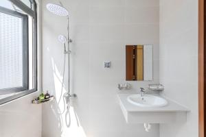 a white bathroom with a sink and a shower at 222 ROSÉ Hotel in Phú Quốc +35 photos