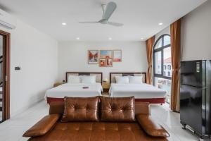 two beds in a room with a couch and a tv at 222 ROSÉ Hotel in Phu Quoc