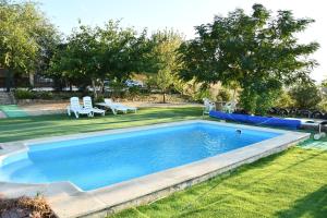 a swimming pool in a yard with two lawn chairs at Casa Rural La Loma in Cabeza del Buey +28 photos