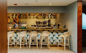 a bar with four stools in front of a counter at Hotel Lucine in Galveston