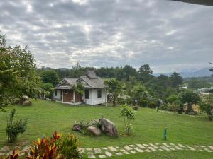 a small house in a grassy field next to a house at Pai Love & Baan Chonphao Resort in Pai
