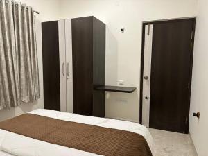 a bedroom with a bed and a black cabinet at Passaddhi Serviced Apartment T2 in Mysore
