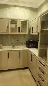 una cocina con armarios blancos y fregadero en شقة فاخرة VIP حي الوادي, en Riad