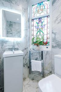 Hilltop Serviced Apartments - Stockport في ستوكبورت: حمام مع حوض ونافذة زجاجية ملطخة