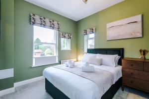 a bedroom with green walls and a bed with white pillows at Hilltop Serviced Apartments - Stockport in Stockport