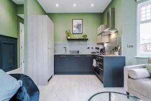 a kitchen with blue cabinets and green walls at Hilltop Serviced Apartments - Stockport in Stockport