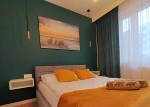 ein Schlafzimmer mit einer grünen Wand und einem Bett mit orangefarbenen Kissen in der Unterkunft Apartament nr15 z parkingiem podziemnym in Toruń