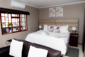 a bedroom with a white bed and a couch at Kleinplasie Guesthouse in Springbok