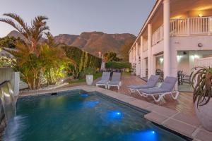 a swimming pool with lounge chairs and a house at Oude Schuur Boutique Guesthouse in Hermanus
