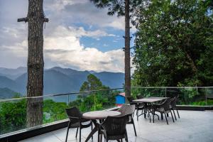 a balcony with tables and chairs and a view of mountains at The Golden Sunrise Hotel in Nainital