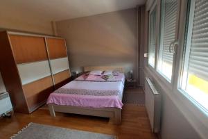 um quarto com uma cama com lençóis cor-de-rosa e uma janela em My grandma's apartment (Skopje center) em Skopje