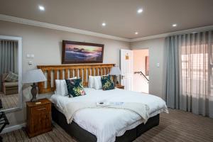 a bedroom with a large bed with a wooden headboard at Guesthouse De Tijger Lodge in Parow
