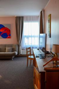 ein Wohnzimmer mit einem Sofa und einem Schreibtisch mit einem Laptop in der Unterkunft Viešbutis Ventainė in Ventė