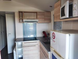 a small kitchen with a refrigerator and a sink at Sun Sea camping le Bosc in Saint-Cyprien
