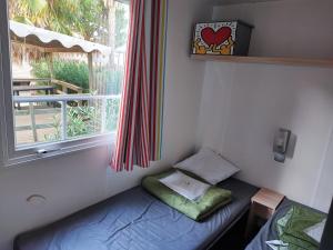 asiento junto a la ventana en una habitación con cama y ventana en Sun Sea camping le Bosc en Saint-Cyprien