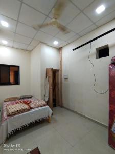 Shree Radhesh Bhakt Niwas في باندهاربور: غرفة نوم بسرير في غرفة بها مروحة