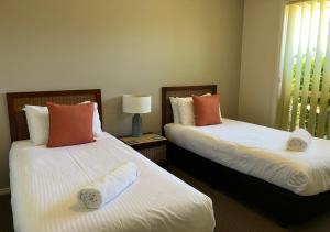 dwa łóżka siedzące obok siebie w pokoju w obiekcie Captain's Quarters Bermagui w mieście Bermagui