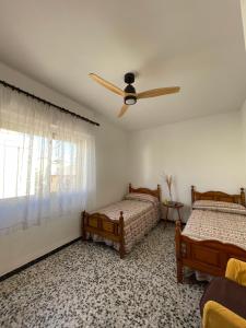 a bedroom with two beds and a ceiling fan at Amplio apartamento junto al mar in Calabardina