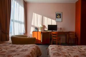 a hotel room with a bed and a desk with a computer at Viešbutis Ventainė in Ventė