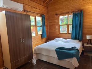 a bedroom with a bed with blue curtains and a window at Likya Yanartaş Bungalow in Kemer