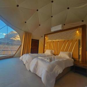 sypialnia z dużym łóżkiem i dużym oknem w obiekcie Salman Zwaidh Camp w mieście Wadi Rum