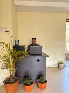 a man sitting at a desk with a laptop computer at Sushrita Hillview Homestay in Guwahati