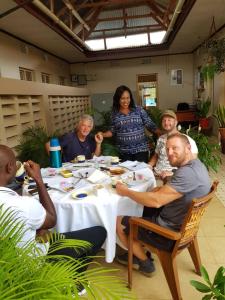 un grupo de personas sentadas alrededor de una mesa comiendo en WEST ORANGE LODGE, en Moshi