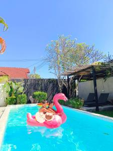 twee mensen rijden op een roze flamingo in een zwembad bij Apantree pool villa Than Ing Doi in Hang Dong