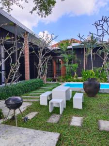 een tuin met witte banken en een grill voor een huis bij Apantree pool villa Than Ing Doi in Hang Dong