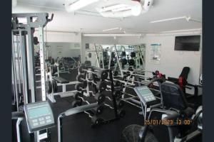 a gym with a bunch of cardio equipment in it at Dwell @ 22, Oceanfront Apartment in Bargara