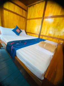 a large bed in a room with wooden walls at Eco Floating Farm Stay Cai Beo in Cat Ba